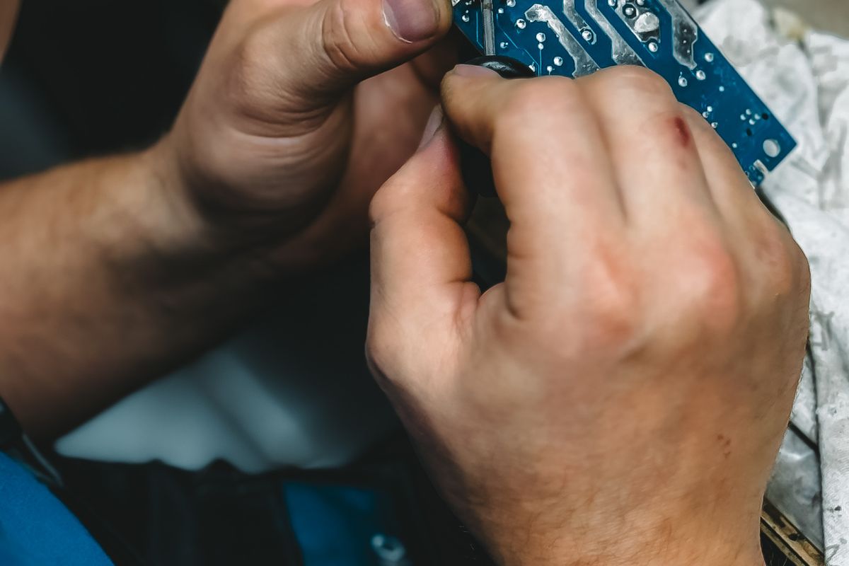 Técnico trabajando con precisión sobre una tarjeta electrónica